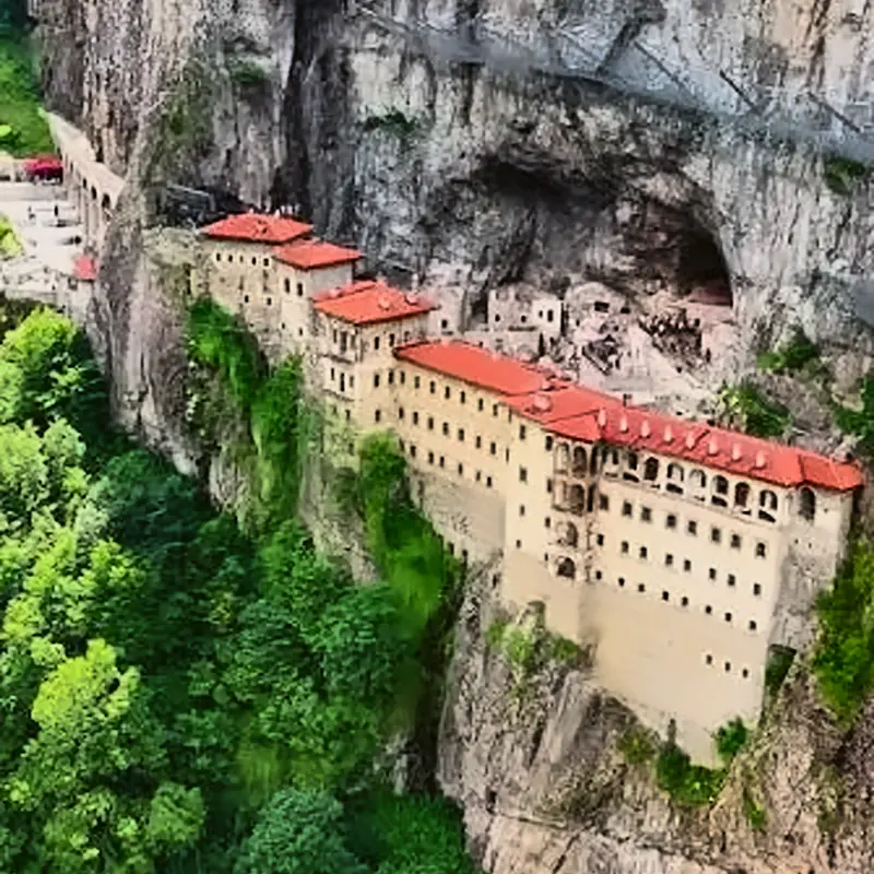 Altındere Vadisi'nde yeşil ormanın üstünde dik kayalığa tutunmuş Sümela Manastırı